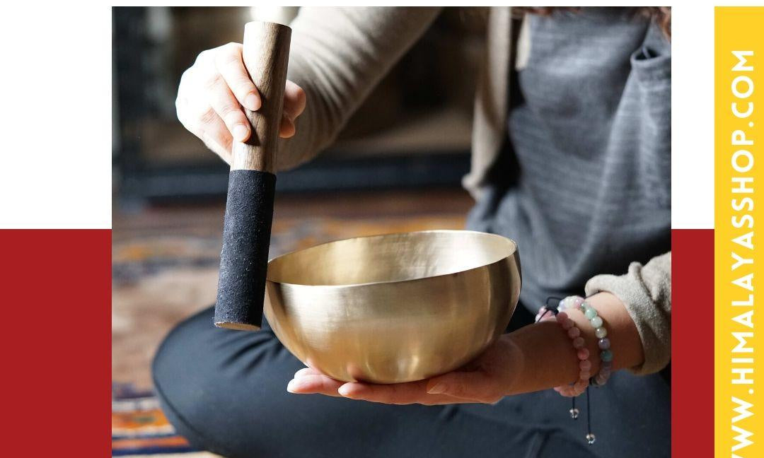 Playing a singing bowl with a wooden mallet